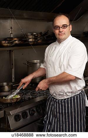 Stock Photo - Male Chef Preparing Meal On Cooker In Restaurant Kitchen. Fotosearch