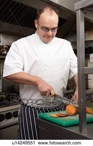 Stock Image - Male Chef Preparing Vegetables In Restaurant Kitchen. Fotosearch