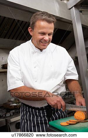 Stock Image - Male Chef Preparing Vegetables In Restaurant Kitchen. Fotosearch