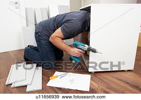 Stock Photo - Man Assembling Flat Pack Furniture. Fotosearch