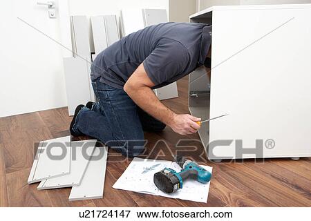 Stock Photo - Man Assembling Flat Pack Furniture. Fotosearch
