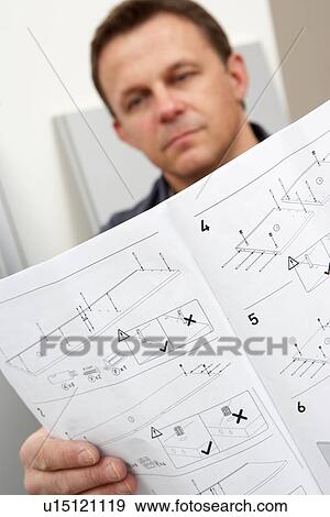 Stock Photo - Man Reading Assembly Instructions For Flat Pack Furniture. Fotosearch