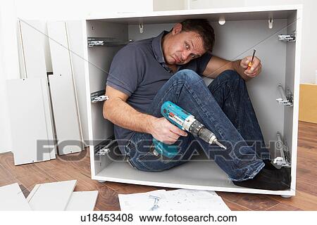 Stock Photo - Man Trapped Whilst Assembling Flat Pack Furniture. Fotosearch