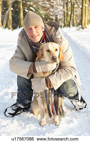 Stock Photograph - Man Walking Dog Through Snowy Woodland. Fotosearch