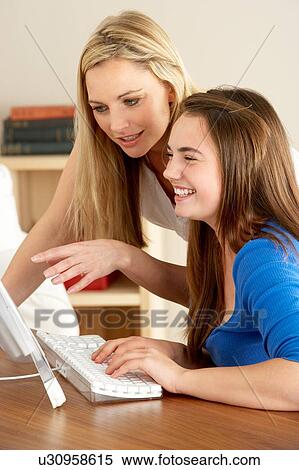 Stock Photography - Mother And Teenage Daughter At Home Using Computer. Fotosearch