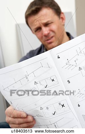 Stock Image - Puzzled Man Reading Assembly Instructions For Flat Pack Furniture. Fotosearch