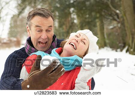 Stock Image - Senior Couple Having Snowball Fight In Snowy Woodland. Fotosearch