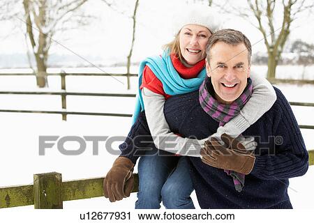 Stock Image - Senior Couple Standing Outside In Snowy Landscape. Fotosearch