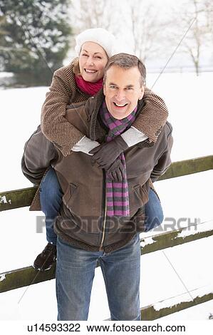 Stock Image - Senior Couple Standing Outside In Snowy Landscape. Fotosearch