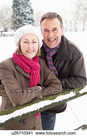 Stock Image - Senior Couple Standing Outside In Snowy Landscape. Fotosearch