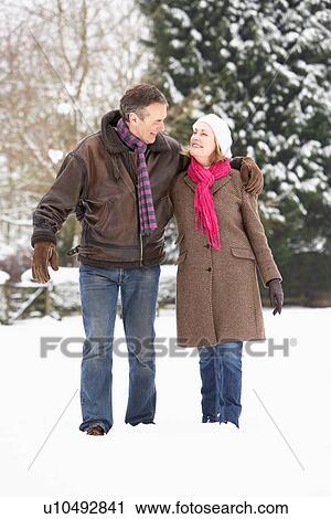 Stock Image - Senior Couple Walking In Snowy Landscape. Fotosearch