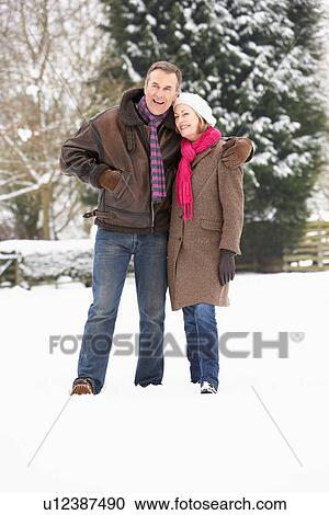 Stock Image - Senior Couple Walking In Snowy Landscape. Fotosearch