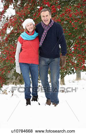 Stock Photo - Senior Couple Walking Through Snowy Woodland. Fotosearch