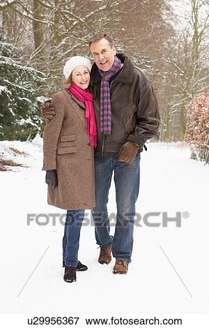 Stock Photo - Senior Couple Walking Through Snowy Woodland. Fotosearch