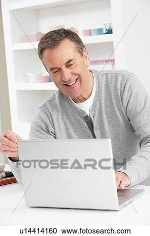 Stock Image - Senior Man Using Laptop At Home. Fotosearch
