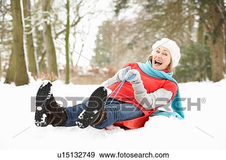 Stock Photo - Senior Woman Sledging Through Snowy Woodland. Fotosearch