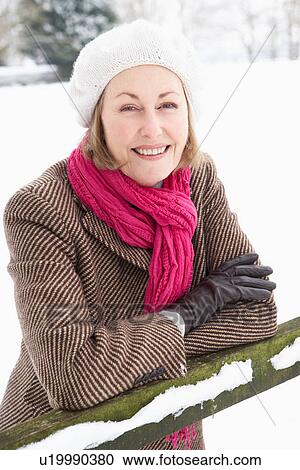 Stock Image - Senior Woman Standing Outside In Snowy Landscape. Fotosearch