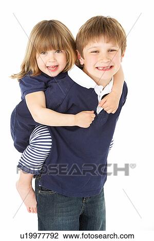 Stock Image - Studio Portrait Of Brother Giving Sister Piggy Back. Fotosearch