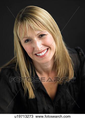 Stock Image - Studio Portrait Of Young Woman Against Black Background. Fotosearch
