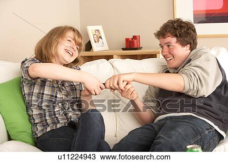 Stock Image - Teenage Couple Arguing Over TV Remote. Fotosearch