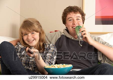 Teenage Couple Sitting On Sofa Watching TV View Large Photo Image Picture - Teenage Couple Sitting On Sofa Watching TV. Fotosearch