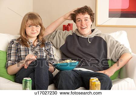 Stock Image - Teenage Couple Sitting On Sofa Watching TV. Fotosearch