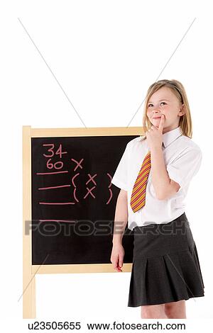 Stock Photography - Thoughtful Female Student Wearing Uniform Next To Blackboard. Fotosearch