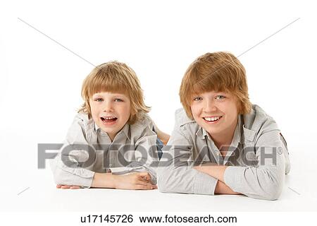 Stock Photograph - Two Young Boys Lying On Stomach In Studio. Fotosearch