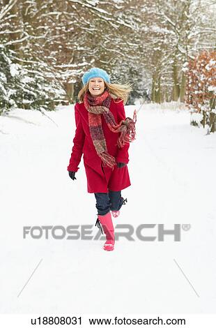 Stock Image - Woman Walking Through Snowy Woodland. Fotosearch