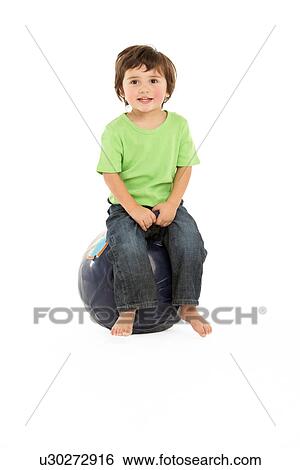 Stock Photograph - Young Boy Having Fun On Inflatable Hopper. Fotosearch