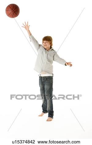 Stock Image - Young Boy Jumping With Basketball In Studio. Fotosearch