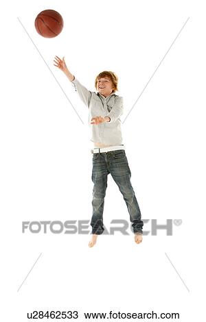 Stock Image - Young Boy Jumping With Basketball In Studio. Fotosearch