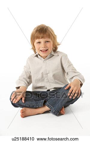 Stock Image - Young Boy Sitting In Studio. Fotosearch