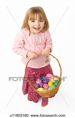 Stock Image - Young Girl Carrying Basket Filled With Easter Eggs. Fotosearch