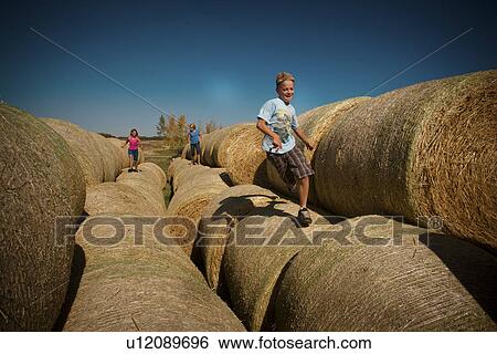 Stock Photograph - 3 farm kids on large straw bales, Redvers, Saskatchewan, Canada. Fotosearch