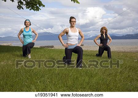 Stock Image - 3 women practicing yoga on beach, Vancouver, BC. Fotosearch