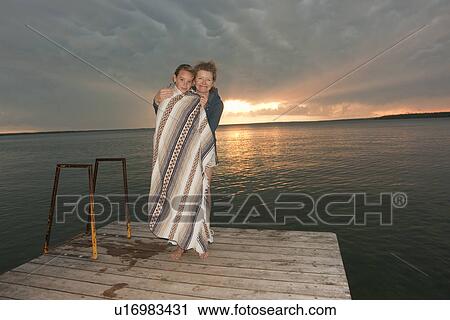 50-s mom with teen wrapped in blanket on dock by Clear Lake at sunset, Riding Mountain National Park, Manitoba, Canada View Large Photo Image Stock Image - 50-s mom with teen wrapped in blanket on dock by Clear Lake at sunset, Riding Mountain National Park, Manitoba, Canada. Fotosearch