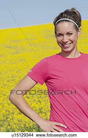 Athletic woman stands in front blooming canola field, Manitoba, Canada View Large Photo Image Picture - Athletic woman stands in front blooming canola field, Manitoba, Canada. Fotosearch
