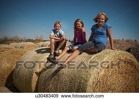 Boy (12) girl (10) and girl (12) seated on bales of straw; Redvers, Saskatchewan, Canada View Large Photo Image Stock Photo - Boy (12) girl (10) and girl (12) seated on bales of straw; Redvers, Saskatchewan, Canada. Fotosearch
