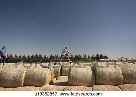 Boy jumping over space between bales; Redvers, Saskatchewan, Canada View Large Photo Image Stock Photo - Boy jumping over space between bales; Redvers, Saskatchewan, Canada. Fotosearch