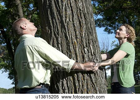 Stock Photography - Couple hold hands around large trees, Assiniboine Park, Winnipeg, Canada. Fotosearch