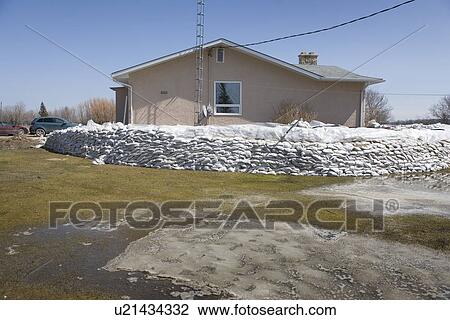 Stock Image - Dyke of sandbags around rural home to protect from Red River floodwaters, rural Manitoba. Fotosearch