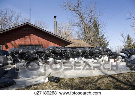 Stock Photo - Dyke of sandbags around rural home to protect from Red River floodwaters, rural Manitoba. Fotosearch