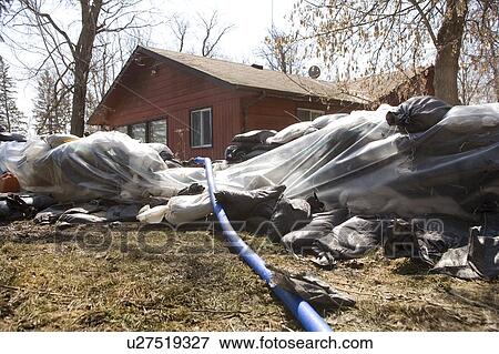 Stock Photo - Dyke of sandbags around rural home to protect from Red River floodwaters, rural Manitoba. Fotosearch