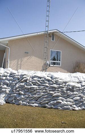 Stock Photograph - Dyke of sandbags around rural home to protect from Red River floodwaters, rural Manitoba. Fotosearch