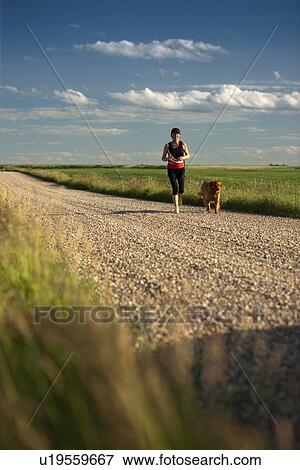 Stock Photo - Female runner and dog, on rural road, Saskatchewan. Fotosearch
