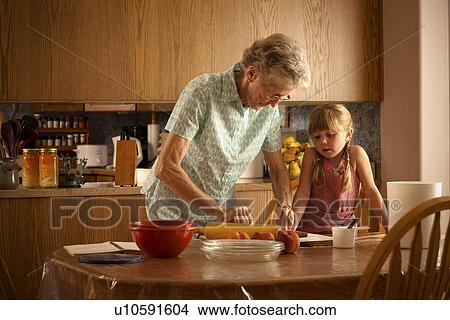 Picture - Five year old girl and her great-grandmother roll out pastry; Redvers, Saskatchewan, Canada. Fotosearch