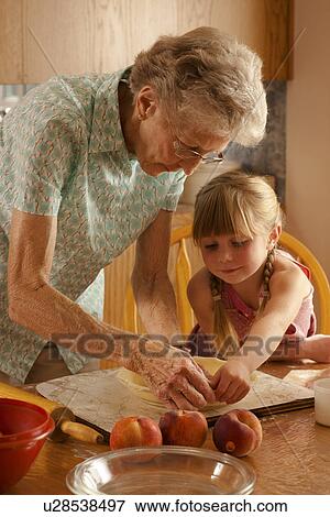 Stock Photo - Five year old girl helping great grandmother prepare pastry; Redvers, Saskatchewan, Canada. Fotosearch