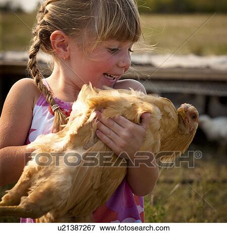 Stock Photo - Five year old girl holding heritage breed of free range chicken; Redvers, Saskatchewan, Canada. Fotosearch