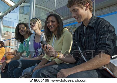 Stock Photo - Group of teens seated on bench in transit shelter, Winnipeg, Canada. Fotosearch